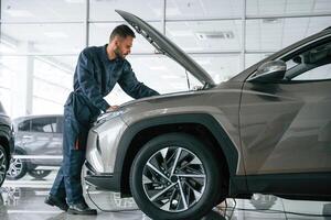 Fixing, the ,vehicle. Side view. Car repairman is in the garage with automobile photo