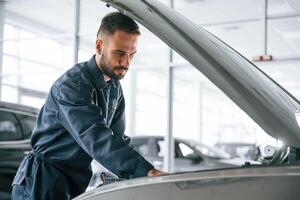 Side, view, hood, is opened.. Car, repairman is in the garage with automobile photo