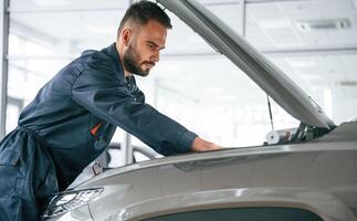 Focused, on, fixing the vehicle. Car repairman is in the garage with automobile photo