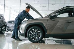Focused on fixing, the vehicle. Car repairman is in the garage with automobile photo