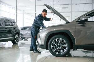 Busy car repairman,, is in the garage with automobile, fixing it photo