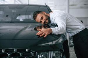 Embracing the ,car. Worker in formal clothes is in the auto salon photo