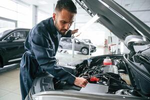 Busy car repairman ,is in the garage with automobile, fixing it photo