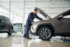 Focused, on fixing the vehicle. Car repairman is in the garage with automobile photo