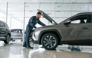Fixing the, vehicle. Side ,view. Car repairman is in the garage with automobile photo