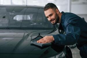 Process of, polishing the surface with cloth. Car repairman is in the garage with automobile photo