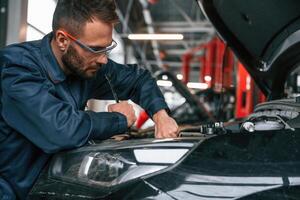 Car repairman,, is in the garage with automobile photo