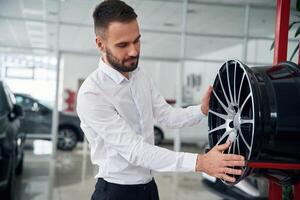 Worker, in formal clothes is in the auto salon photo