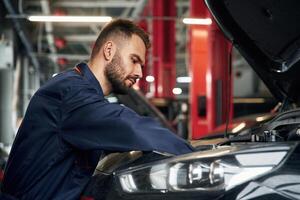 Busy ,car, repairman is in the garage with automobile, fixing it photo