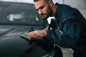Polishing, the vehicle. Car repairman is in the garage with automobile photo