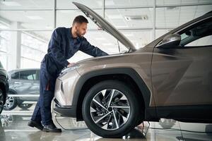 Fixing the vehicle. Side ,view. Car repairman is in the garage with automobile photo