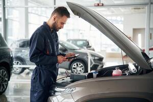 View, from the side. Car repairman is in the garage with automobile photo