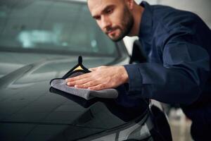 Process, of polishing ,the surface with cloth. Car repairman is in the garage with automobile photo