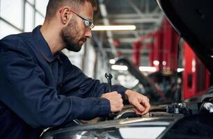 Hood, is ,opened, fixing. Car repairman is in the garage with automobile photo