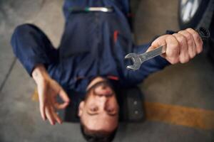 On, the, ground with tool. Car repairman is in the garage with automobile photo