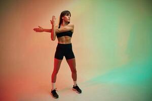 Standing and, doing exercises. Young woman in fitness clothes is in the studio photo