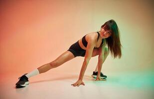 Front view, doing stretching of the, legs. Young woman in fitness clothes is in the studio photo