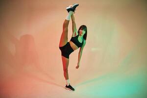 Standing and doing exercises. ,.Young woman in fitness clothes is in the studio photo