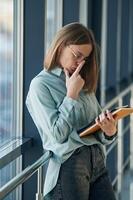Reading the information from tablet. Young woman in airport hall photo