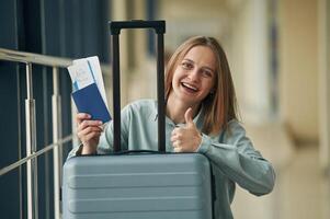 Can't wait for the flight. With tickets, and, luggage. Young woman in airport hall photo