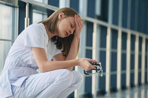 Tired, feeling bad, exhausted.,, Female doctor in white coat is in the hall photo