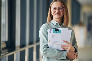 Many of the documents,, in hands. Young woman in airport hall photo