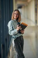 Drink, notepad ,and tablet ,,in hands. Young woman in airport hall photo