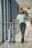 Happy, tourist with luggage. Young woman in airport hall photo