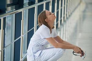 Tired,, feeling bad, exhausted. Female doctor in white coat is in the hall photo