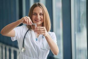Test tubes, with liquid in them. Female doctor in white coat is in the hall photo