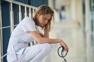 Sitting,, taking a break, tired,. Female doctor in white coat is in the hall photo