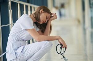 Sitting,, taking ,a break, tired. Female doctor in white coat is in the hall photo