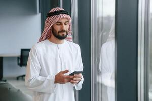 In ,the ,office with phone. ..Successful Muslim businessman in traditional outfit photo