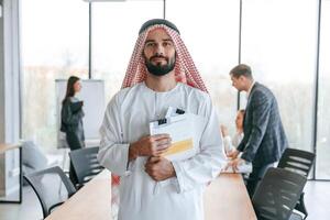 People,behind Muslim businessman that ,is, in traditional outfit with colleagues ,,in office photo