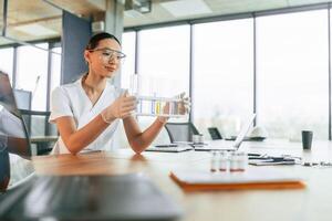 Working, with, bunch, of, test tubes. Female doctor in white coat is indoors photo