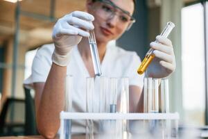 Experimenting with chemicals in test tubes.. Female doctor in white coat is indoors photo