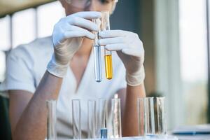 Experimenting with chemicals, in ,test tubes. Female doctor in white coat is indoors photo
