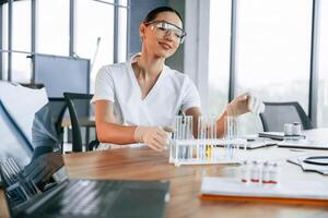 Many of, the, test tubes with liquid on the table. Female doctor in white coat is indoors photo