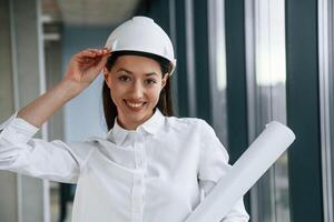 Female ,,architect in hard hat and in white clothes is indoors photo