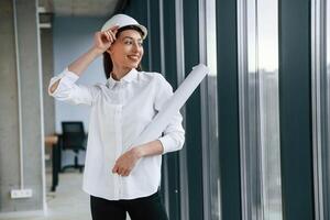 Female ,architect in hard hat and in white clothes is indoors photo