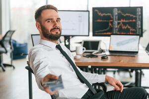 Money in hand. Businessman is sitting by computer and working in the office photo