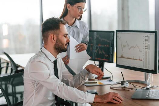 corredores con monitores ,con gráficos en el mesa. dos empleados son trabajando en el oficina juntos foto