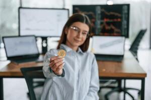 Digital, currency, conception of stock. Golden coin in hand. Businesswoman is working in the office photo