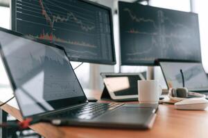 Table with laptop and monitors with graphs data in the office photo