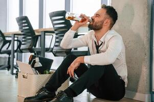 Drinking alcohol,. Unemployed ma,n is ,with personal belongings after being fired photo