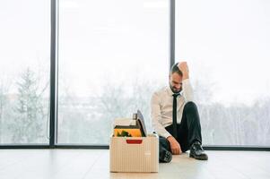 By the ,panoramic ,windows, sitting. Unemployed man is with personal belongings after being fired photo