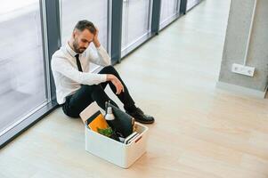 By the panoramic windows, sitting... Unemployed man is with personal belongings after being fired photo