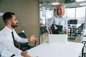 Woman is giving the man box with his belongings, guy getting fired photo