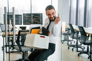 Showing, middle ,finger. Unemployed, man is with personal belongings after being fired photo