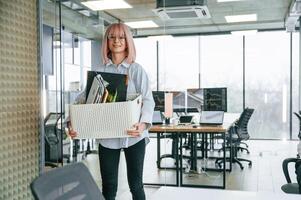 Standing ,and smiling... Unemployed ,woman with pink hair is with personal belongings after being fired photo